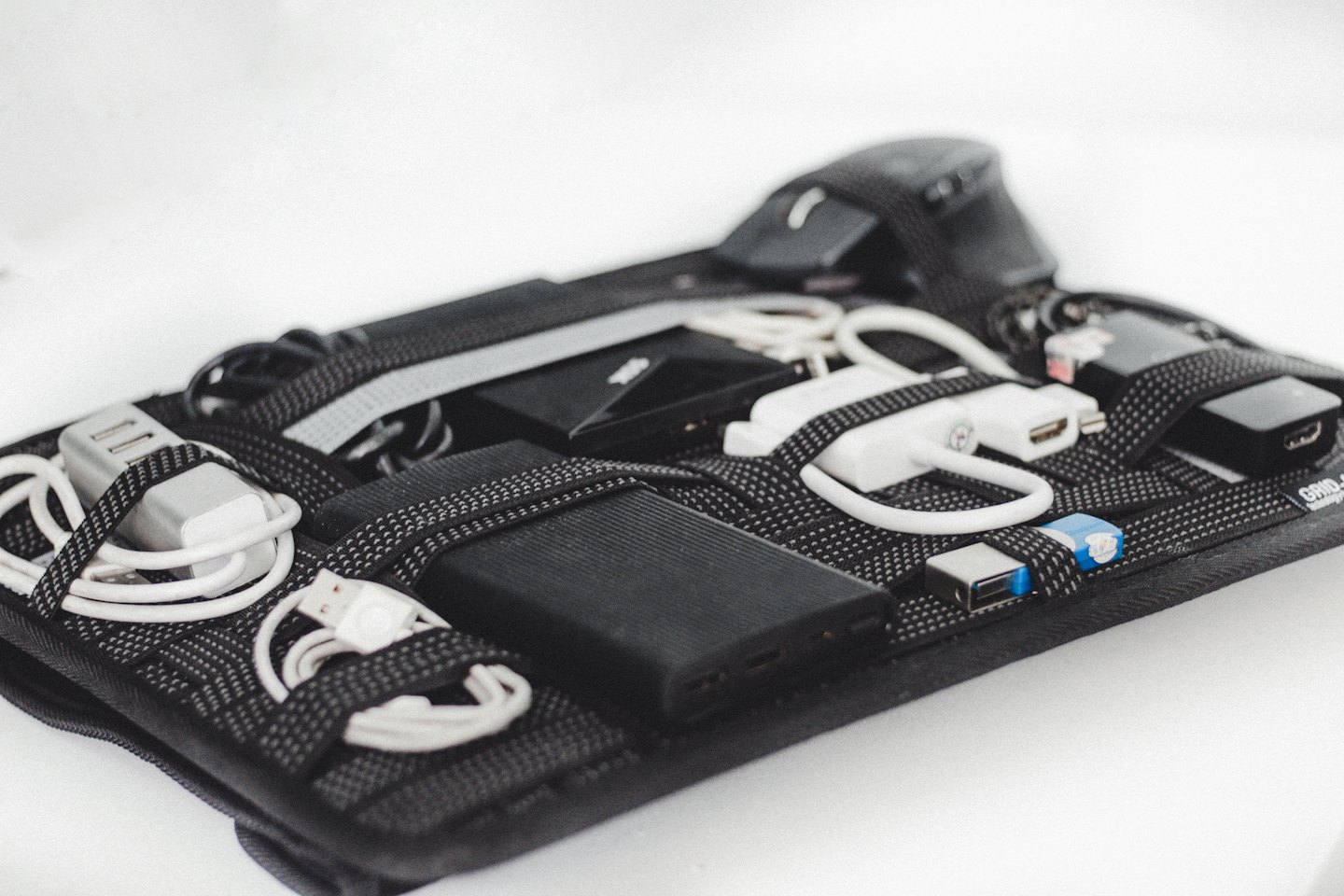Accesorios electrónicos sujetos con correas elásticas dentro de un organizador de tela.