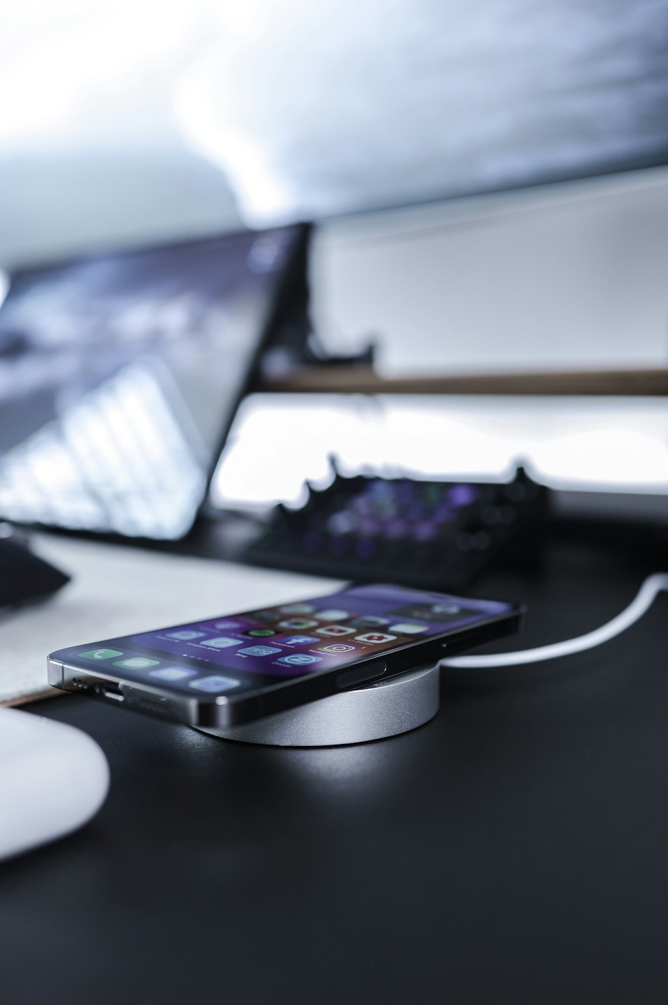 Un smartphone se carga de forma inalámbrica en una base sobre un escritorio.