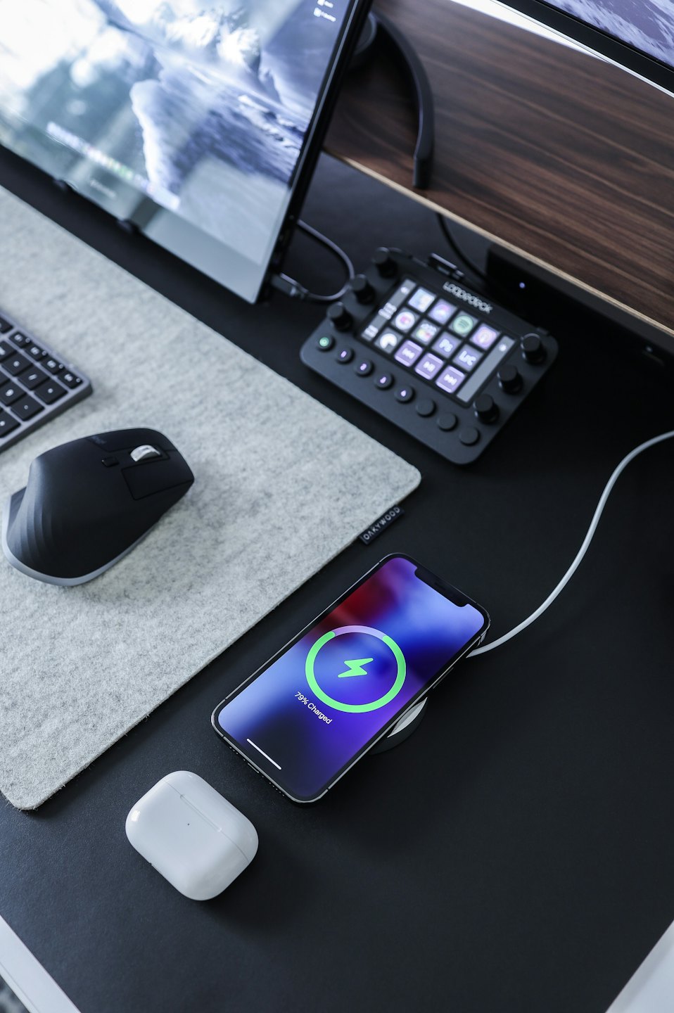 Escritorio moderno con cargador de smartphone junto a AirPods y teclado.
